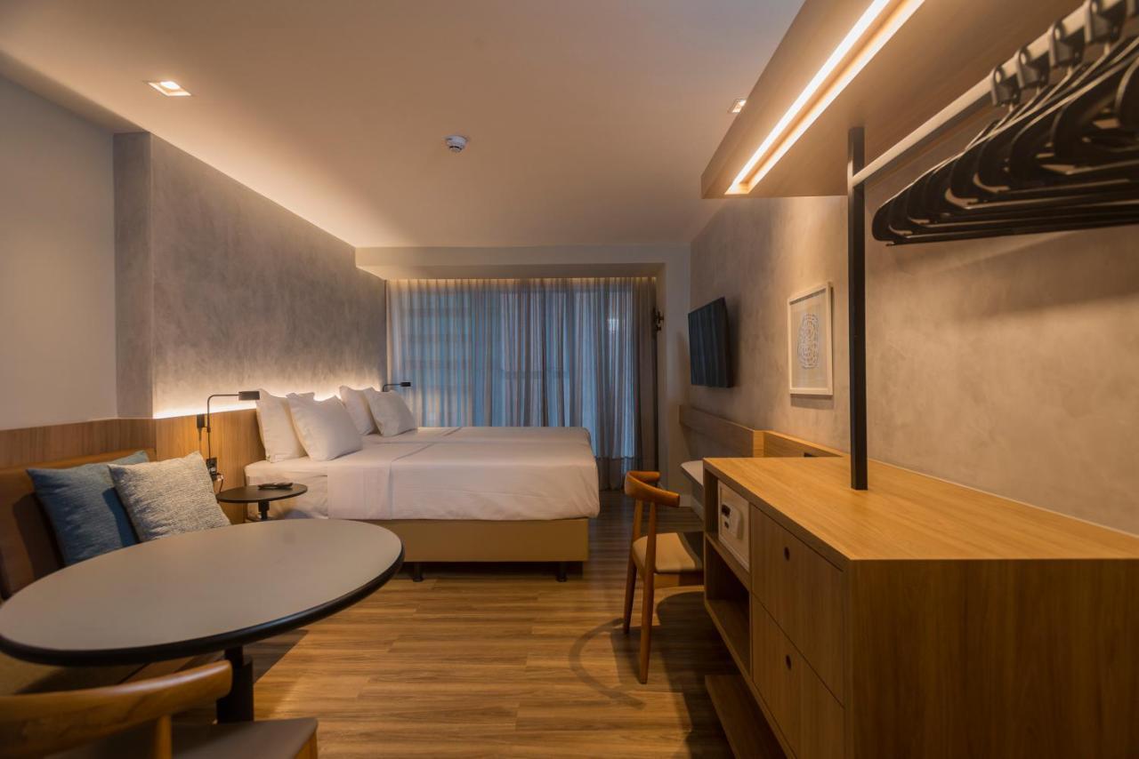 Hotel Luzeiros Fortaleza Exterior foto The photo shows a modern hotel room with a clean and minimalist design. It features two large beds with light-colored bedding, positioned against a wall with a textured finish. There are large windows with sheer curtains allowing natural light to fil