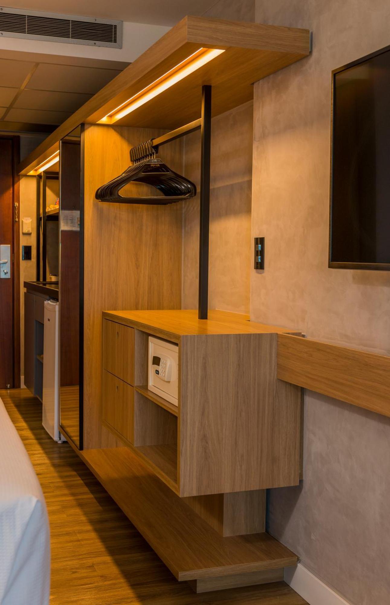 Hotel Luzeiros Fortaleza Exterior foto The photo shows a compact hotel room storage area. It features a wooden dresser with two drawers and a small safe integrated into the design. Above the dresser, there's a hanging rod with a black hanger, likely intended for clothes. A flat-screen tel