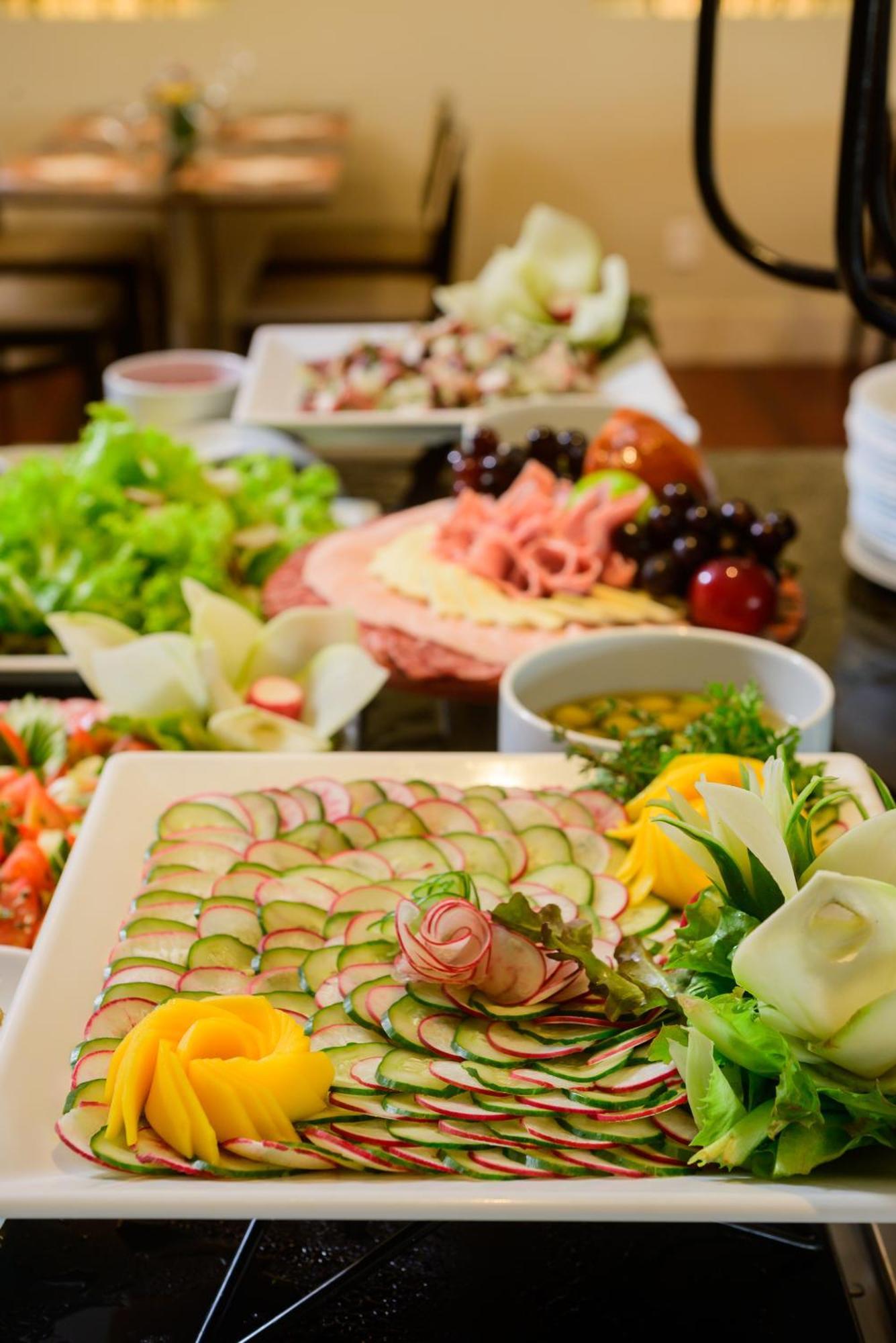 Hotel Luzeiros Fortaleza Exterior foto The photo showcases a beautifully arranged display of food. In the foreground, there's a plate with thinly sliced cucumbers arranged in a decorative pattern, garnished with leafy greens and edible flowers. Surrounding this plate are various other dis