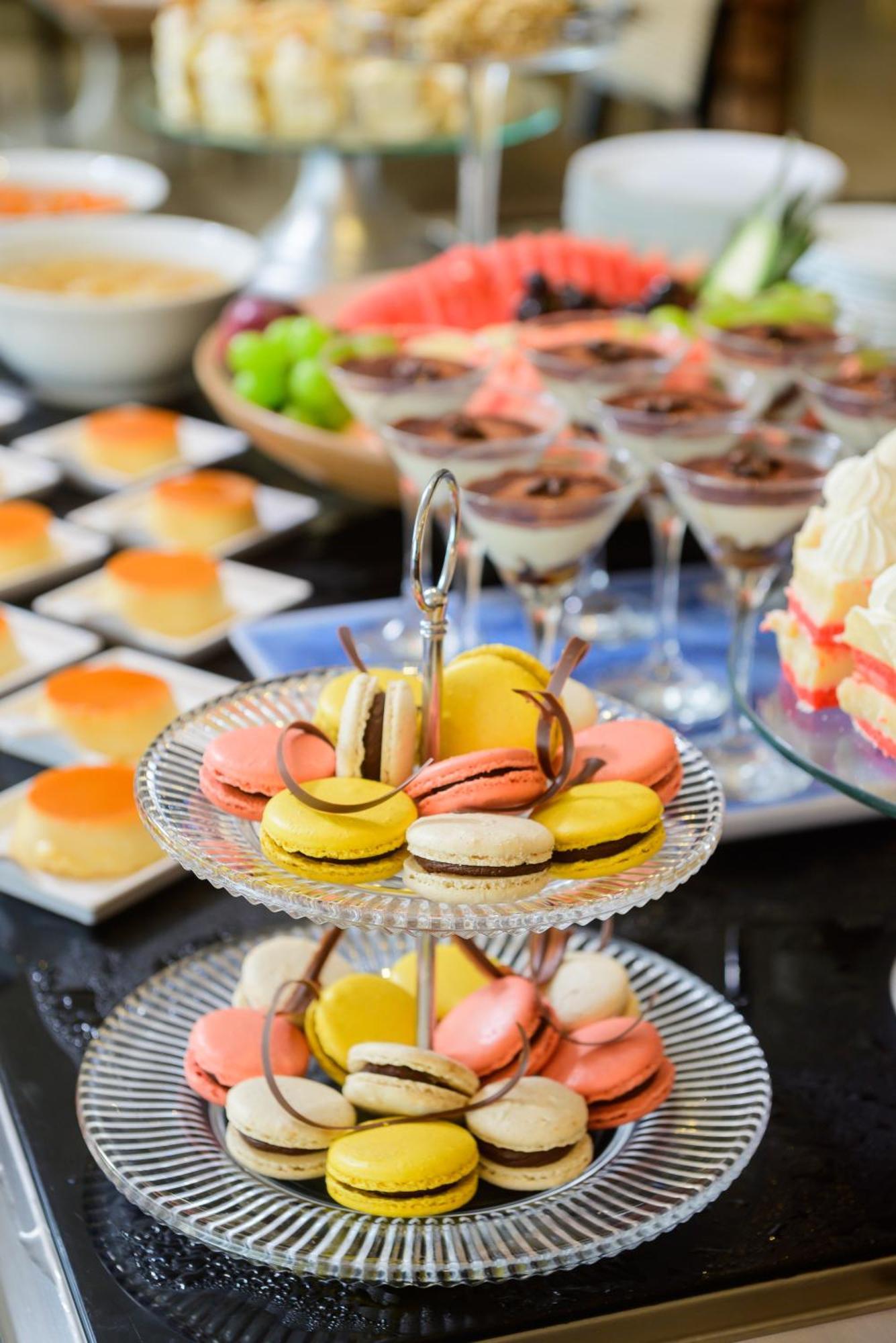 Hotel Luzeiros Fortaleza Exterior foto The photo displays an array of delightful desserts arranged on a table. In the foreground, there is a multi-tiered stand featuring colorful macarons in shades of yellow, pink, and white, some topped with chocolate. In the background, there are small 