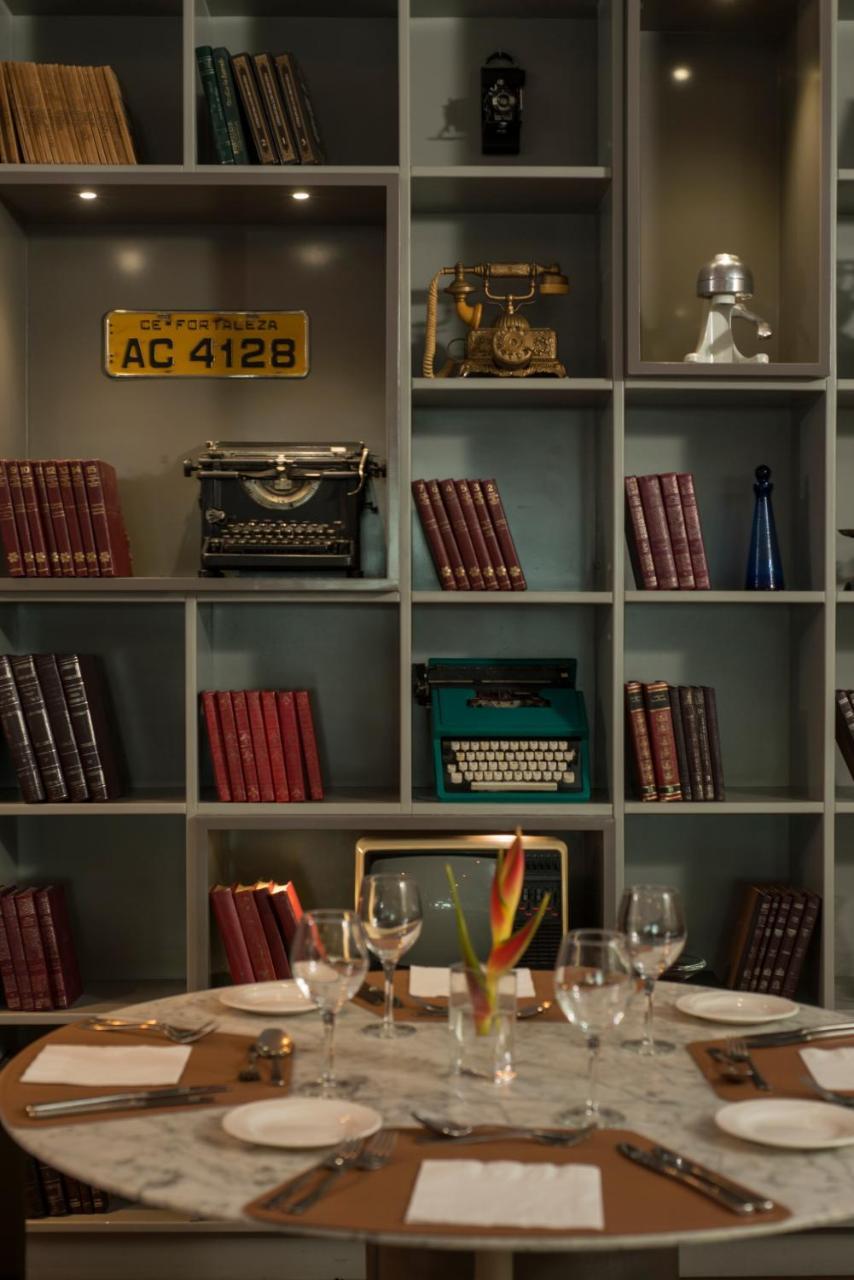 Hotel Luzeiros Fortaleza Exterior foto The photo features a vintage-inspired bookshelf with a grid design. It showcases several items, including:

- Old typewriters, one in black and one in green.
- A collection of books with red covers stacked upright.
- An antique television set.
- A bl